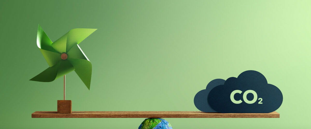 Illustration de l’empreinte carbone industrielle avec une balance entre énergie renouvelable, planète et émissions de CO2
