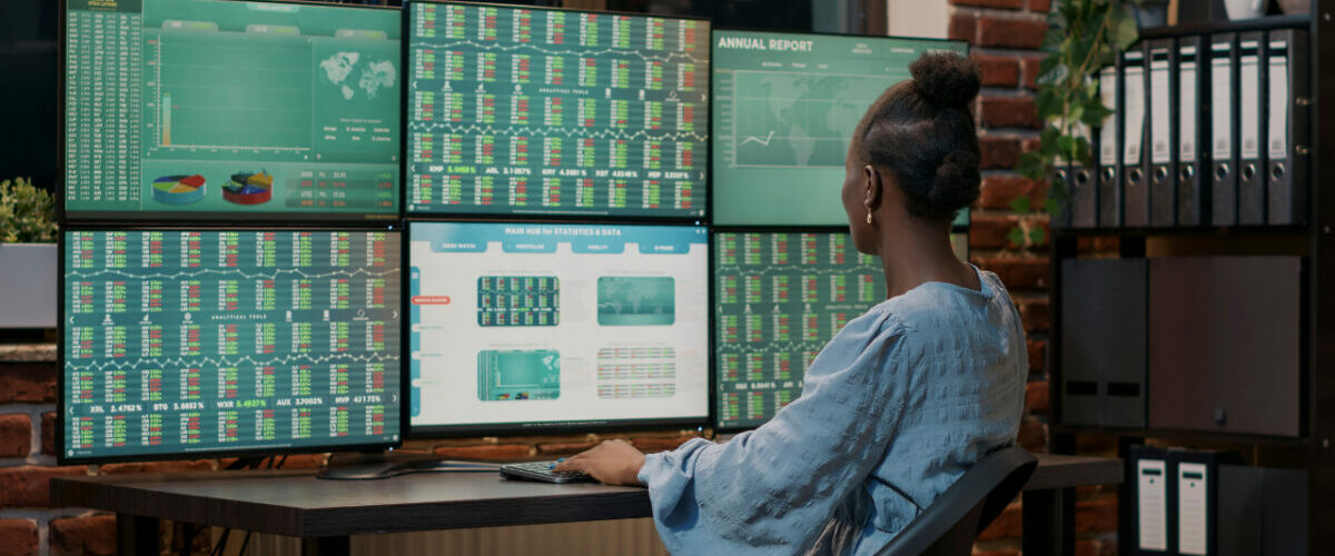 Ingénieure analysant des données de production sur plusieurs écrans pour synchroniser un MES avec un jumeau numérique.